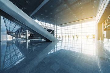 Escalators and corridors of modern office building or airport, glass walls and reflective floor, natural light and flare