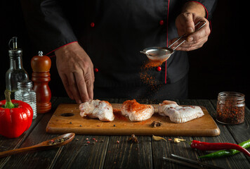 Professional chef adds paprika to raw chicken wings. Cooking chicken nugget in the kitchen with pepper and spices