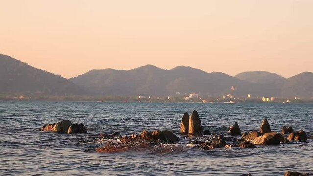 Boulders in the sea with the view of Kep City in the back as seen from Koh Tonsay or Rabbist Island, both popular summer travel destinations in Cambodia