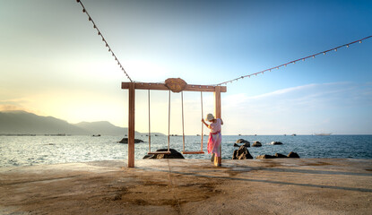 A female tourist relaxes on a swing at a tropical beach at 4-star Hon Co Resort, Ca Na in Ninh province. Thuan, Vietnam. She feels comfortable and happy with the scenery here