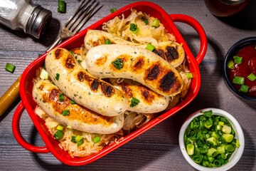 White fried Munich, wurst sausages with fried cabbage or sauerkraut. Oktoberfest, Bavarian summer grill party food portion, with fresh herbs and tomato bbq sauce
