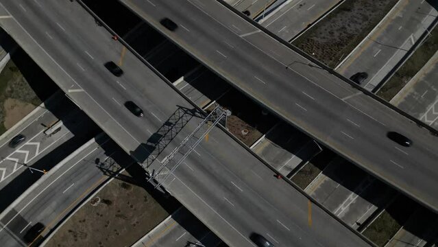 An aerial view high over a highway intersection in Queens, New York on a sunny day. The drone camera tilted downwards, pan left 180 degrees then dolly in over the complicated interchange.