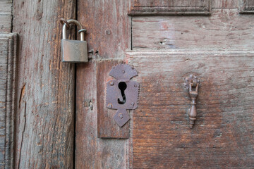 Old rusty iron lock and wrought iron hasp on an old wooden door
