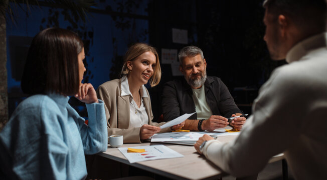 Confident business people brainstorming together, team working at new project in office. Night work