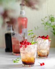 lingonberry cocktail with ice and chocolate in beautiful glasses, branch in blur