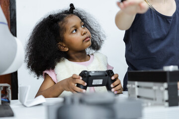Children girl African American holding  joystick education electronic on table at class room. learning innovation electronic for future AI. electric system skill training. STEM education concept.