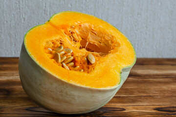 ripe orange pumpkin close-up, cut in half and seeds inside on a wooden table, ripe healthy vitamin diet vegetable.