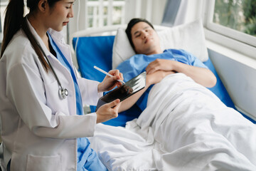 Fototapeta premium Doctor discussing treatment with male patient talking and laughing sitting on examination bed in clinic or hospital.