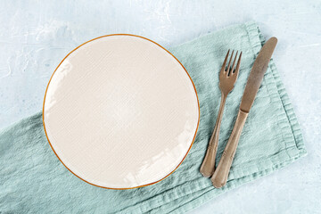An empty white plate with a gold rim, with a fork and a knife, overhead flat lay shot, the concept of dinner