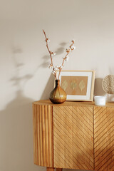 A wooden chest of drawers in a modern interior stands against a white wall. Home decor...