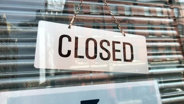 A shop closed sign, concept for business hours, cost of living, signage and economy. Also an inner security roller shutter gate is closed form security. Copy space, static shot.