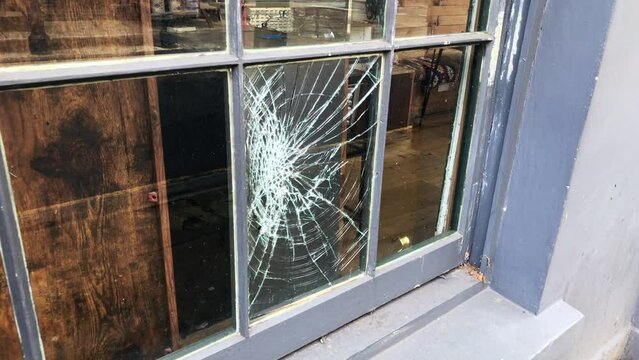 A broken shop window, lower centre glass pane cracked. Concept for street crime, vandalism, insurance, criminal activity, burglary and anti social violent behaviour. Static shot.