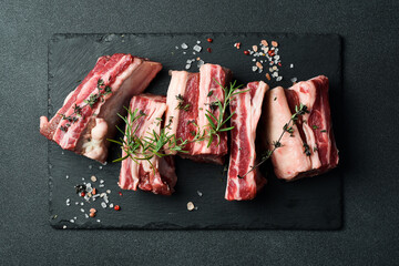 Raw sliced veal short spare loin ribs on a marble board. Black background. Top view. Copy space