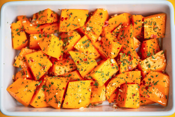 pumpkin pieces with spices in a baking dish in the oven