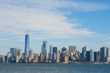 Fototapeta na wymiar Gorgeous view of the Manhattan skyline with the Freedom Tower over a calm sea on a sunny day