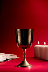 christian chalice with candles and bible red background