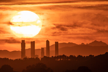 The sun sets behind the skyscrapers of the skyline of Madrid