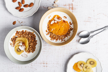 Bowls of yogurt with granola, kiwi, and orange fruits,  top view. Healthy  breakfast