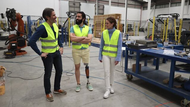 workers engineers of a robotics factory, man with a prosthetic leg. Social integration at work.