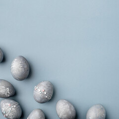 Festive Easter background. Gray-blue Easter eggs with stars on a blue table. Banner with a place for text. Top view.
