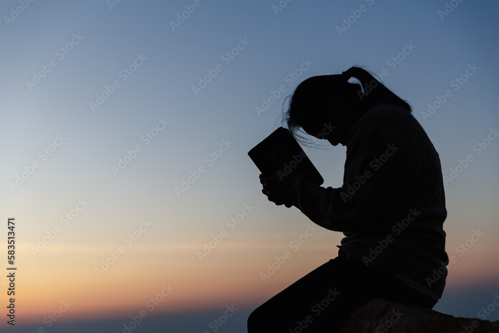 Poster Silhouette of woman kneeling down praying for worship God at sky background. Christians pray to jesus christ for calmness. In morning people got to a quiet place and prayed. copy space.