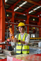 Asian younng worker man working with remote control's operating crane or lifting beam in factory