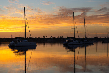 Naklejka na ściany i meble Silhouette of sailboats anchored in marina during a beautiful sunrise, St. Augustine, Florida