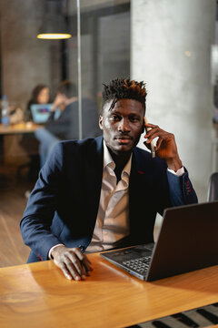 Portrait of successful businessman in office. Young smiling man talking to the phone