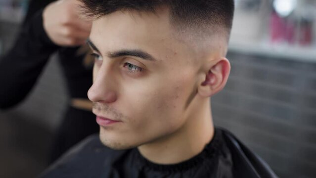 Close-up portrait of a young attractive man in a barber shop who gets a haircut