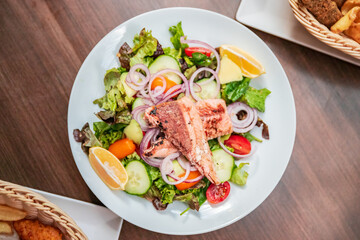 Shot of a salat vegan dish on a white plate with salmon on top. very colorfull dish healthy vegetarian with salmon fish
