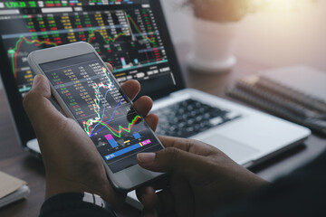 Trade and finance concept.Businessman checking stock market by his smartphone and laptop.trading graph, financial investment concept.