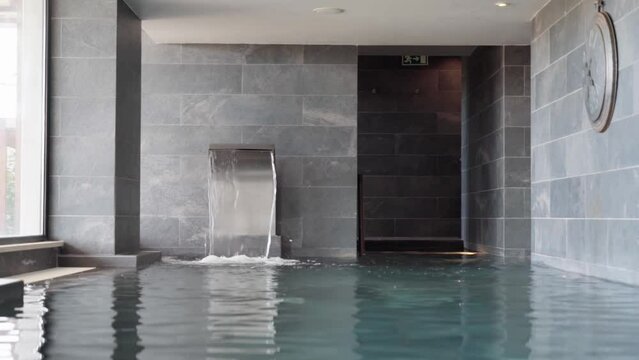 Indoor swimming pool with falling water fountain for spa clients.