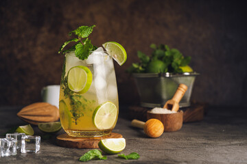 Iced Mojito cocktail long rum drink with fresh mint, fresh thyme, lime juice, cane sugar and soda on dark abstract background. Summer iced beverage and cocktail