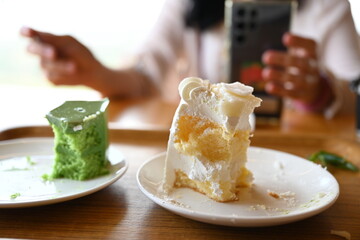 The white and green triangular cakes were eaten until a small amount was left. The coconut cake and green tea cake were all left on a white plate after eating full.
