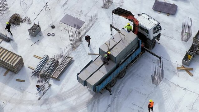 Workers hooking a concrete block on a small truck crane at the construction site