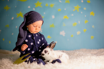 Little child, baby boy with cute white bunny and moon on a blue star and moon background