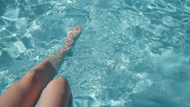 Foot movement in the pool with clear turquoise water while relaxing in the hotel.