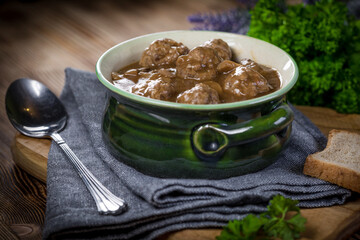 Pork meatballs with noodles in a green bowl.