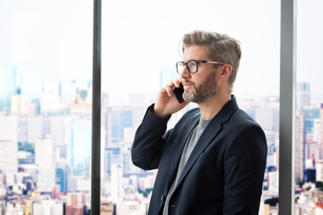 Executive businessman standing in a glass office and having a business call