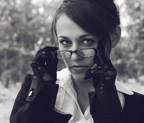 close-up portrait of a girl lowering her glasses a little looks strictly at the viewer the girl's hands in black mesh gloves