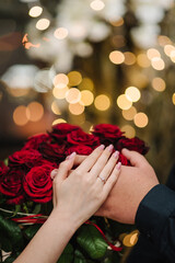 Marriage proposal. Will you marry me. She said yes. A couple hand with wedding ring on a bouquet of...