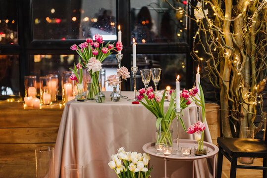 Table setting in restaurant. Romantic date. Luxury candlelight dinner setup table for couple on Valentine's day. Location decoration tulips flowers, decor candles for surprise marriage proposal.