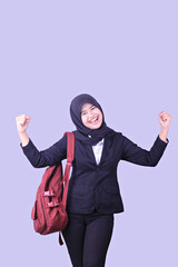 A woman wearing a backpack and celebrating her success