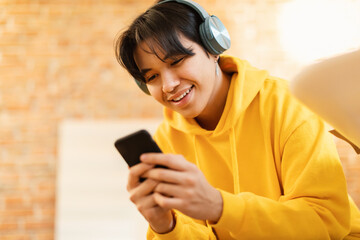 Teenager Guy Using Phone Wearing Earphones Listening Music Online Indoors