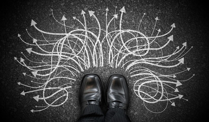 Black business shoes and many winding chalky arrows on asphalt - decision concept