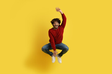 Fototapeta na wymiar Carefree indian guy leaping in the air on yellow