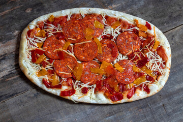 Pizza au chorizo fait maison sur un fond de vielles planches de bois vue en plongée