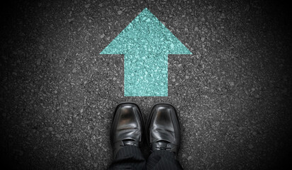 Black business shoes and green chalky arrows on asphalt - forward concept