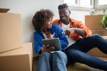 Black Couple Having Fun With Digital Tablet, Choosing Furniture For New Home
