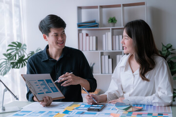 Fototapeta premium Happy young Asian couple enjoying in working time, watching on line chart. Smiling woman Happy.